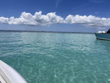 A serene view of a boat cruising through crystal-clear turquoise waters, showcasing the beauty of the open sea and a perfect day for boating.