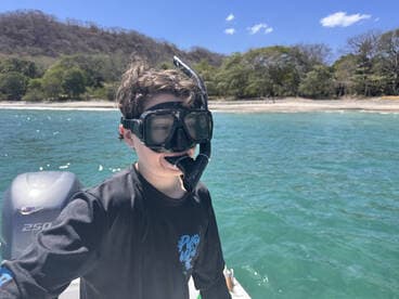 A young boy prepares for an exciting snorkeling adventure in clear blue waters, showcasing the thrill of exploring marine life.