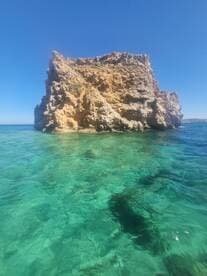 A stunning view of a rocky coastline rising from crystal-clear turquoise waters, perfect for showcasing the natural beauty of the area.