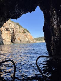 A stunning view from inside a cave, showcasing the rugged coastline and tranquil waters — an ideal spot for exploring natural wonders by boat.