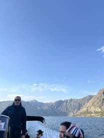 A group of friends enjoys a scenic boat ride with stunning mountain views in the background, perfect for exploring beautiful waterways.