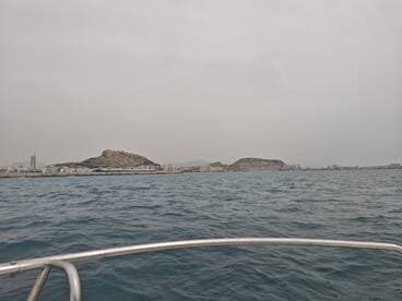 A scenic view of the coastline with a prominent hill and cityscape in the background, captured from a boat — perfect for showcasing the beauty of coastal adventures.