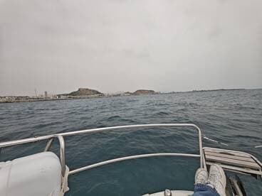 A scenic view from the bow of a boat, showcasing the coastline and rocky hills in the distance — perfect for exploring coastal landscapes.