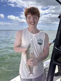 A young man proudly displays his catch while fishing on a boat, showcasing the joy of outdoor adventures and successful fishing trips.