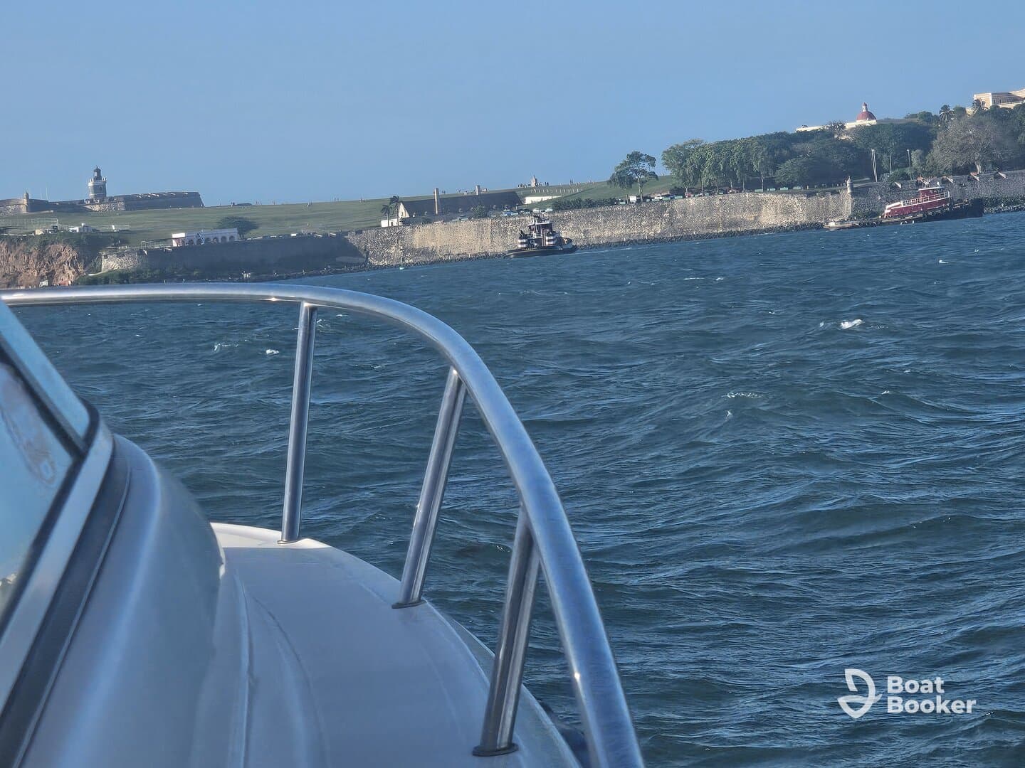 A scenic view of a boat's bow cutting through the waves, with a historic coastal fortification in the background, perfect for showcasing maritime adventures.
