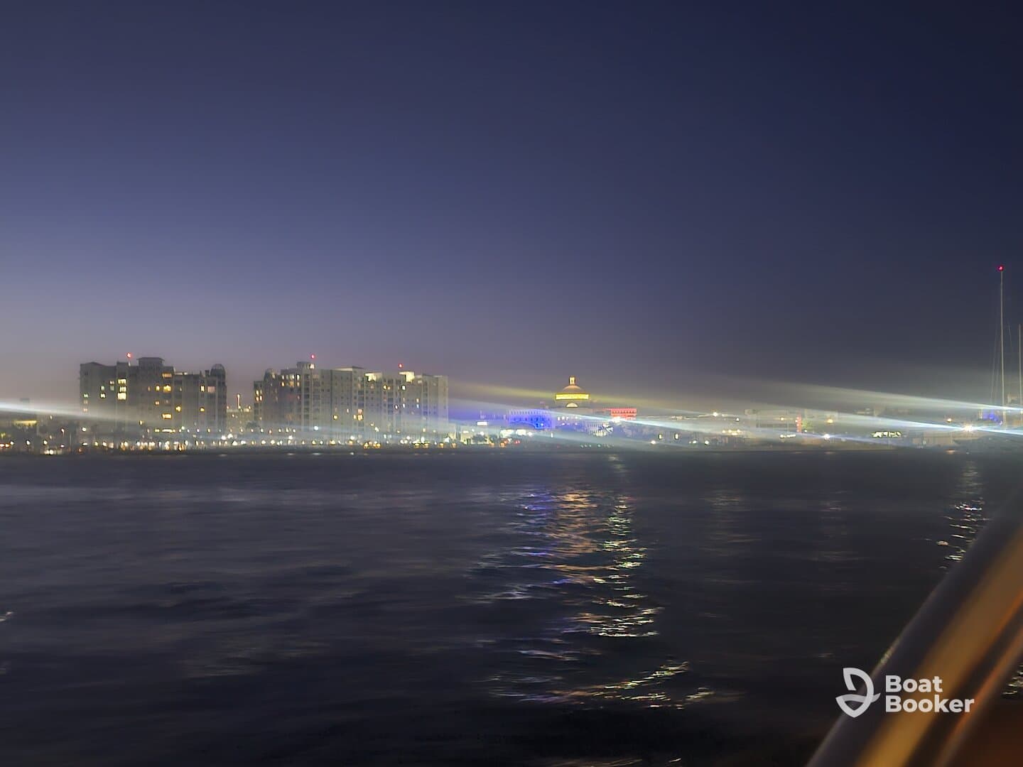 A blurry nighttime view of a waterfront with illuminated buildings, lacking clear focus or identifiable features.