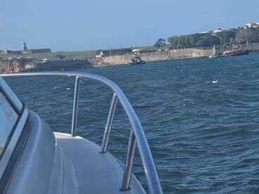 A scenic view of a boat's bow cutting through the waves, with a historic coastal fortification in the background, perfect for showcasing maritime adventures.