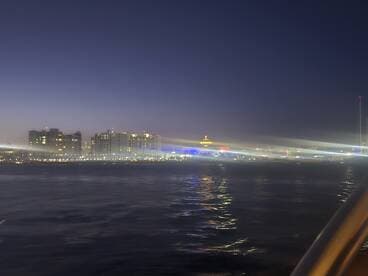 A blurry nighttime view of a waterfront with illuminated buildings, lacking clear focus or identifiable features.