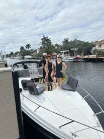 A group of friends poses on the bow of a boat, wearing captain hats and enjoying their time together — perfect for a fun day on the water.