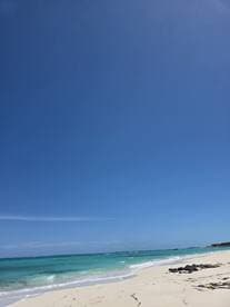 A scenic view of a beach with turquoise waters and a clear blue sky, perfect for relaxation and beach activities.