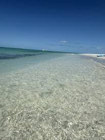 A stunning view of crystal-clear waters meeting a sandy beach, perfect for a relaxing day in paradise. Ideal for beach lovers and those seeking scenic escapes.