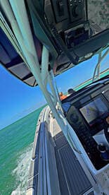 A view from the helm of a boat, showcasing the control console and navigation screen, with passengers visible in the background — perfect for those looking to experience boating adventures.