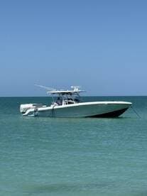 A sleek speedboat anchored in calm turquoise waters, showcasing its design and structure against a clear blue sky.