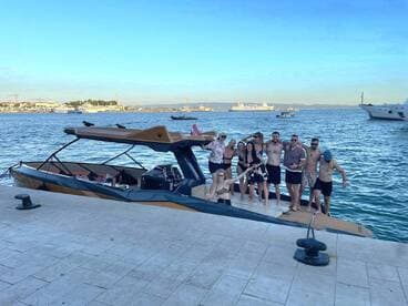 A lively group of friends poses on the deck of a stylish boat at the dock, ready for a fun day on the water. Perfect for celebrations and group outings.