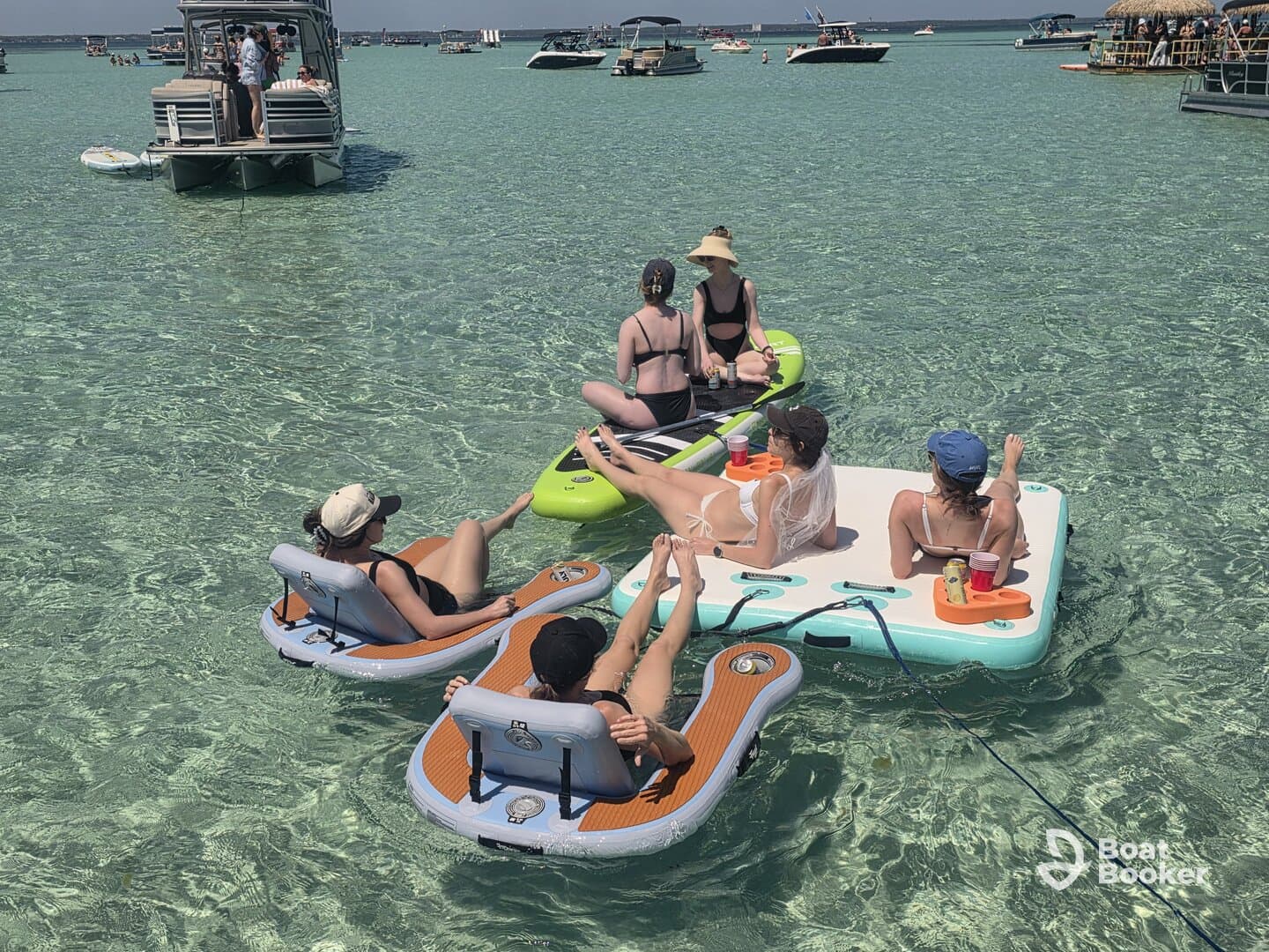 A lively group enjoys a day on floating mats in crystal-clear waters, sipping cocktails and soaking up the sun — the perfect summer getaway.