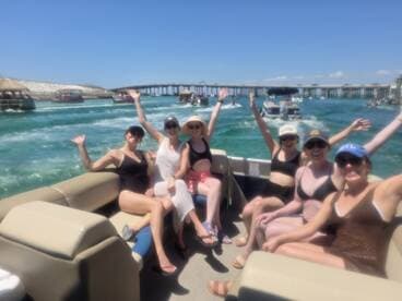 A lively group of friends enjoys a fun day on a pontoon boat, waving and celebrating under the sun — perfect for summer outings and memorable adventures on the water.