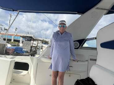 A woman stands inside the cabin of a boat, showcasing the comfortable interior space — perfect for relaxing during a day on the water.