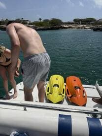 Guests prepare to enjoy jet skiing on a sunny day, with vibrant yellow and orange jet skis ready for action on the boat.