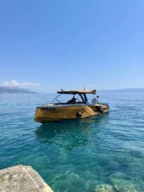 A stylish boat glides through crystal-clear waters, showcasing a perfect day for adventure on the sea.