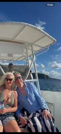 A cheerful couple enjoys drinks aboard a boat under a sunny sky, capturing the essence of a perfect day on the water.