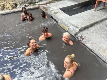 A joyful group enjoys a relaxing soak in natural hot springs, creating memorable moments together in a scenic setting.