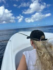 A woman enjoys the view while cruising on a boat, surrounded by the vast ocean and a beautiful sky — a perfect moment for adventure on the water.