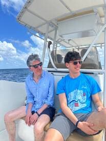 Two men relax on the deck of a boat, enjoying a sunny day on the water. This moment captures the essence of leisure and camaraderie while boating.