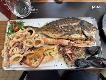 A delicious seafood platter featuring grilled fish, calamari, shrimp, and mussels, perfect for enjoying a meal on board or at a seaside restaurant.