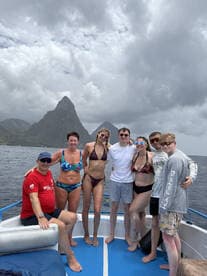 A cheerful group poses on a boat with stunning mountain scenery in the background, capturing the essence of a fun-filled vacation on the water.
