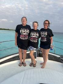 Three friends celebrate their milestone birthdays aboard a boat, showcasing joy and camaraderie against a stunning turquoise backdrop.