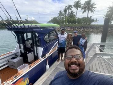 A cheerful group poses for a selfie on the dock next to their fishing boat, capturing the excitement of a day on the water.