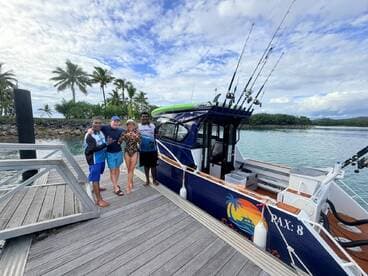 A cheerful group poses for a photo by their fishing boat at the dock, ready for an exciting day on the water. Perfect for fishing adventures and group outings.