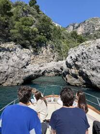 A group of friends enjoys a scenic boat ride through a stunning coastal archway, capturing the essence of adventure on the water.