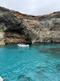 A scenic view of a boat navigating through turquoise waters near a stunning coastal cave, perfect for exploring beautiful marine landscapes.