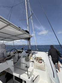 A view of the helm area on a sailing catamaran, showcasing the steering console and crew members preparing for the journey ahead.