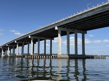 A view of a bridge over water, showcasing its structural design and reflections in the water. The image lacks clarity and focus.
