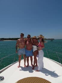 A cheerful group of friends poses together on the bow of a boat, enjoying a sunny day on the water — perfect for memorable outings and celebrations.