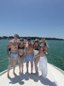 A cheerful group of friends poses together on the deck of a boat, enjoying a sunny day on the water — perfect for summer outings and celebrations.
