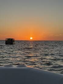 A serene sunset view over the ocean with a boat silhouetted against the vibrant sky, perfect for capturing the tranquility of evening boat rides.