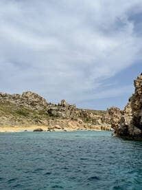 A stunning view of rocky cliffs and a serene beach, showcasing the natural beauty of the coastline — perfect for island hopping adventures.