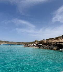 A vibrant scene at a beach with groups of people enjoying the clear turquoise waters, perfect for a day of relaxation and fun in the sun.