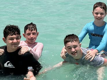 A joyful group of kids enjoys a fun day swimming in clear turquoise waters, capturing the essence of summer adventures.