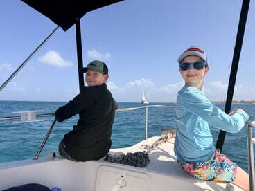 Two kids enjoy a sunny day on a boat, smiling and taking in the ocean views — a perfect family adventure on the water.