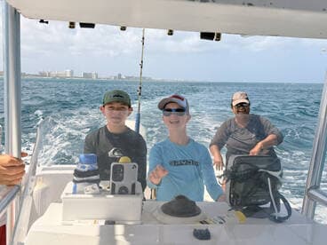 A joyful group of three, including two children, enjoys a day on the water aboard a boat, capturing the excitement of fishing adventures.