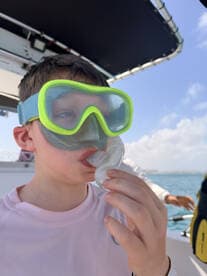 A young boy prepares for snorkeling with a mask and snorkel, showcasing the excitement of underwater exploration on a boating adventure.