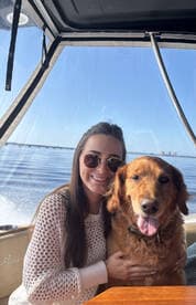 A joyful moment aboard a boat, featuring a woman and her golden retriever enjoying the sunny day together — perfect for pet-friendly boating adventures.
