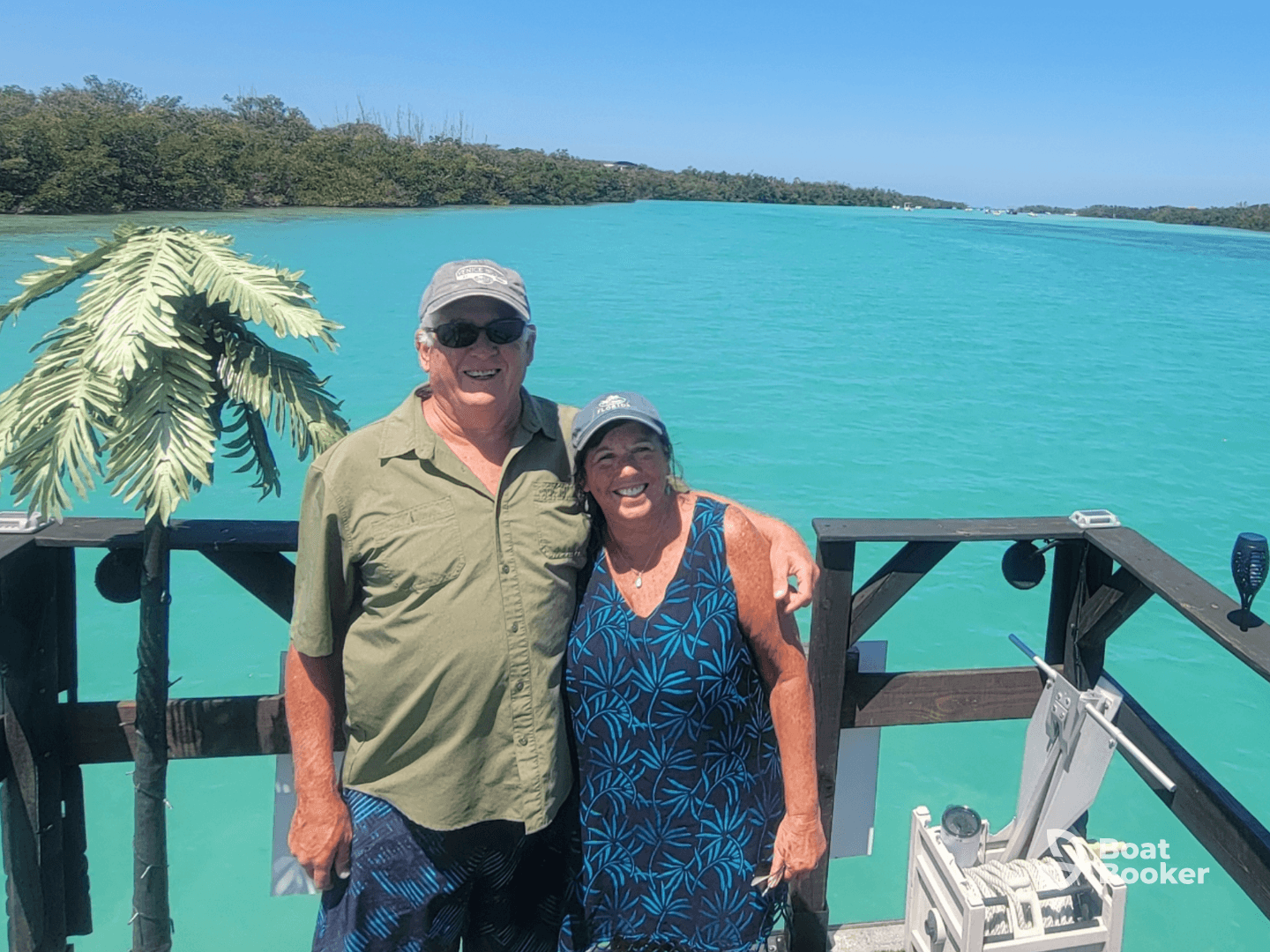 A happy couple poses for a photo against the stunning turquoise waters, capturing a memorable moment during their boating adventure.