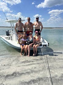 A cheerful group of friends poses on the beach beside their boat, enjoying a sunny day on the water — perfect for summer adventures and memorable outings.
