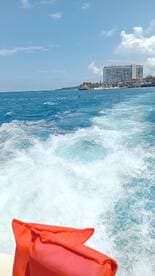 A scenic view of the ocean with waves in the foreground and a hotel in the background, capturing the essence of a vibrant boating experience.