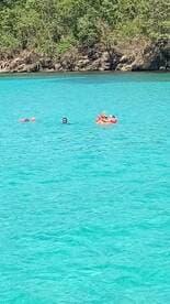 A group enjoys a refreshing swim in crystal-clear turquoise waters, perfect for a fun day in the sun.